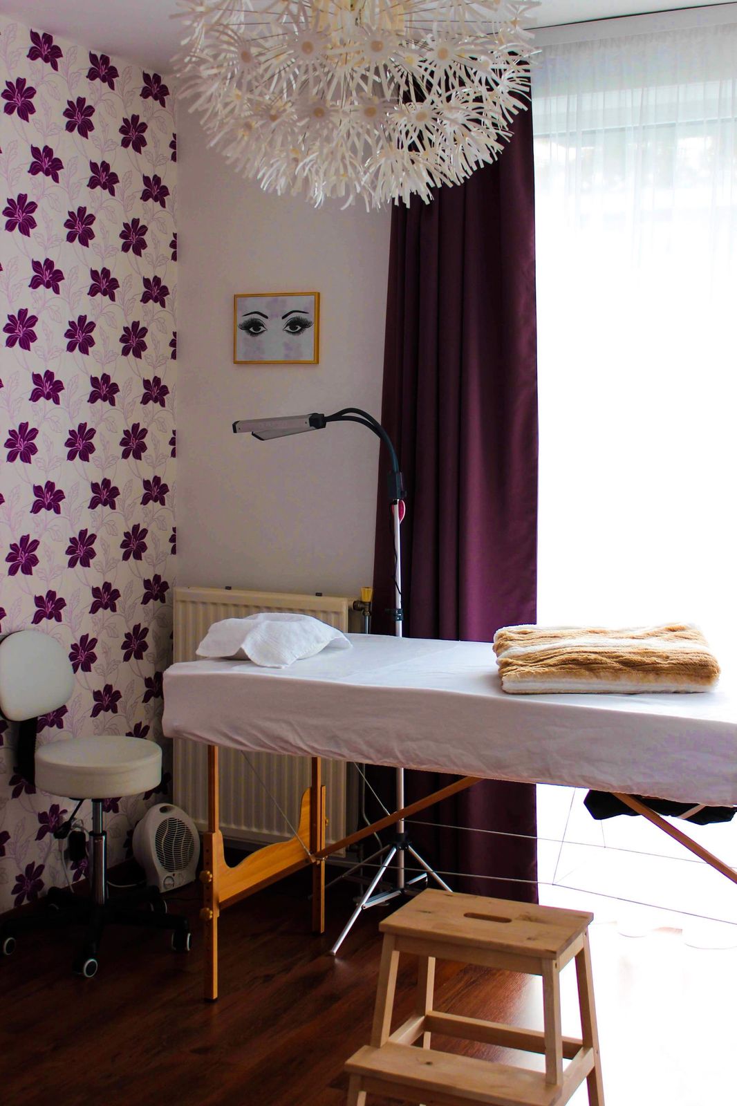 De behandelkamer aan huis: behandelbed met deken, lamp en behang met paarse bloemen